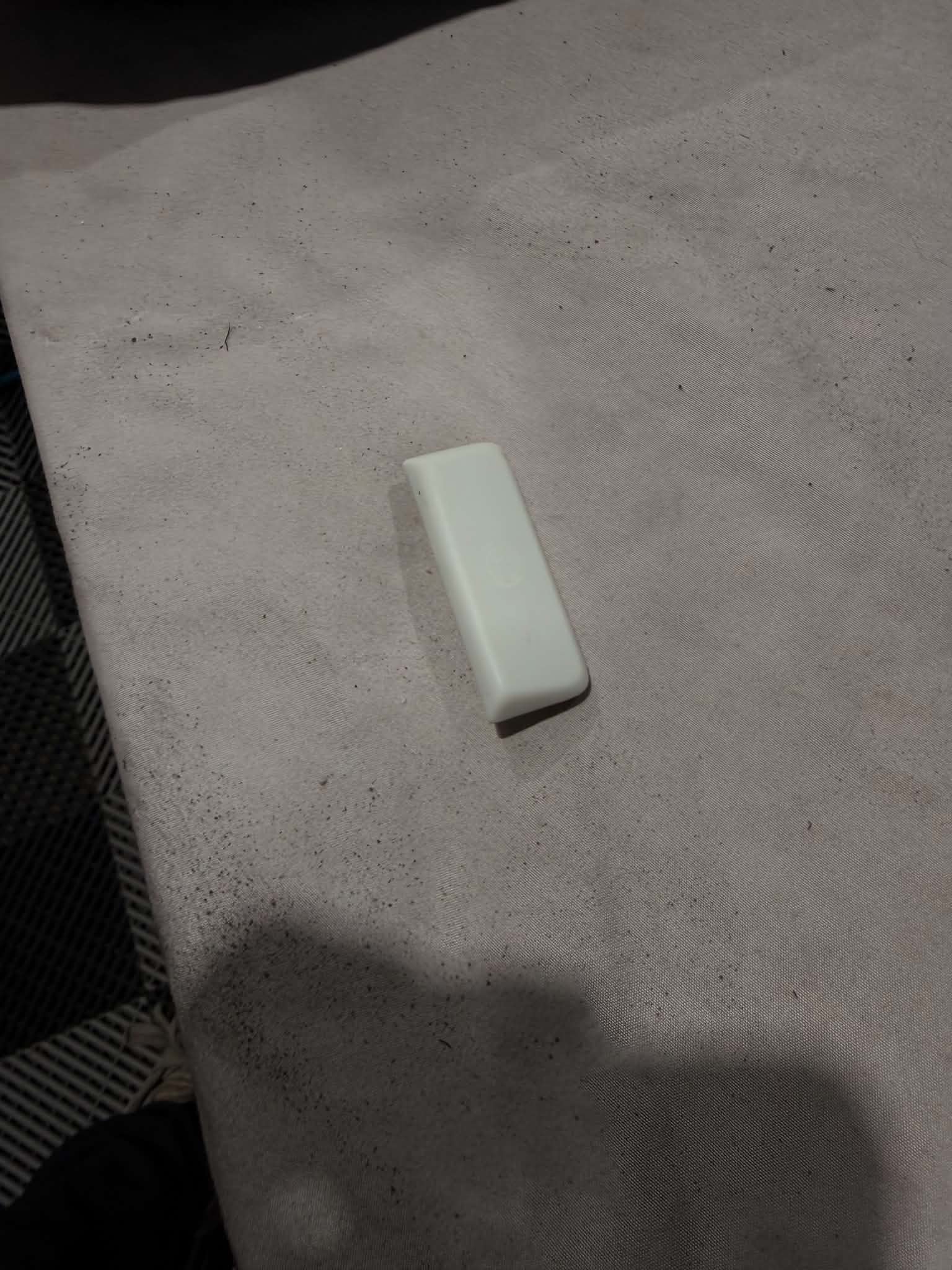 Parking brake button stripped back to its bare white translucent plastic core, the faint outline of the original symbol still visible, ready for recoating