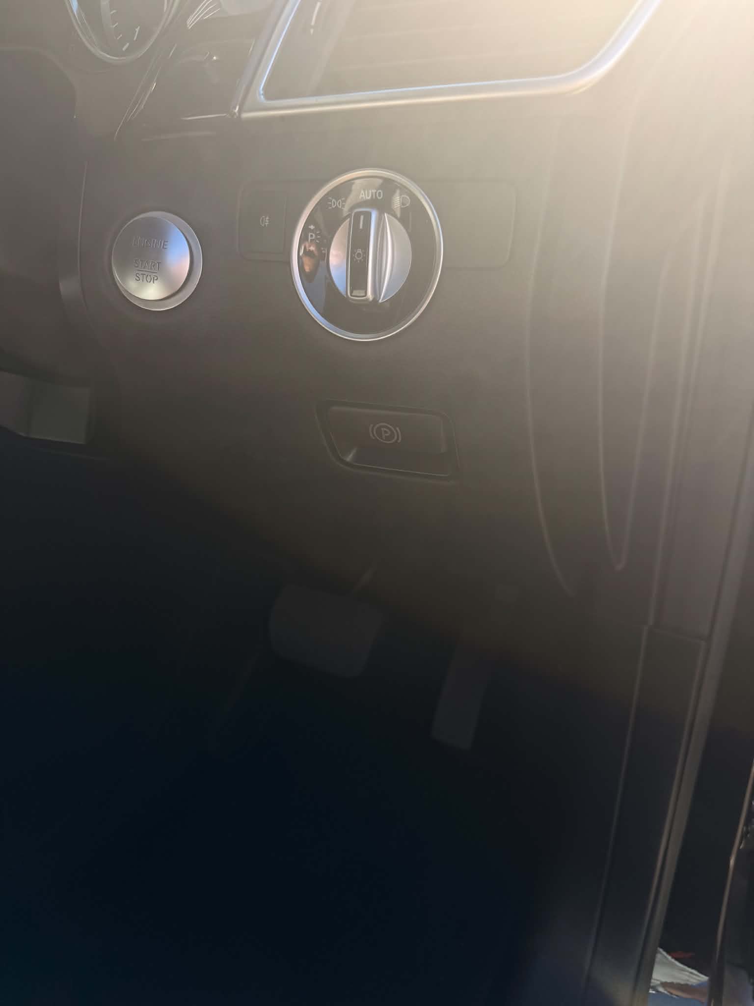 The same parking brake button finished and refitted in the Mercedes dash beside the start stop button and headlight knob, its P symbol laser etched back through the new coating
