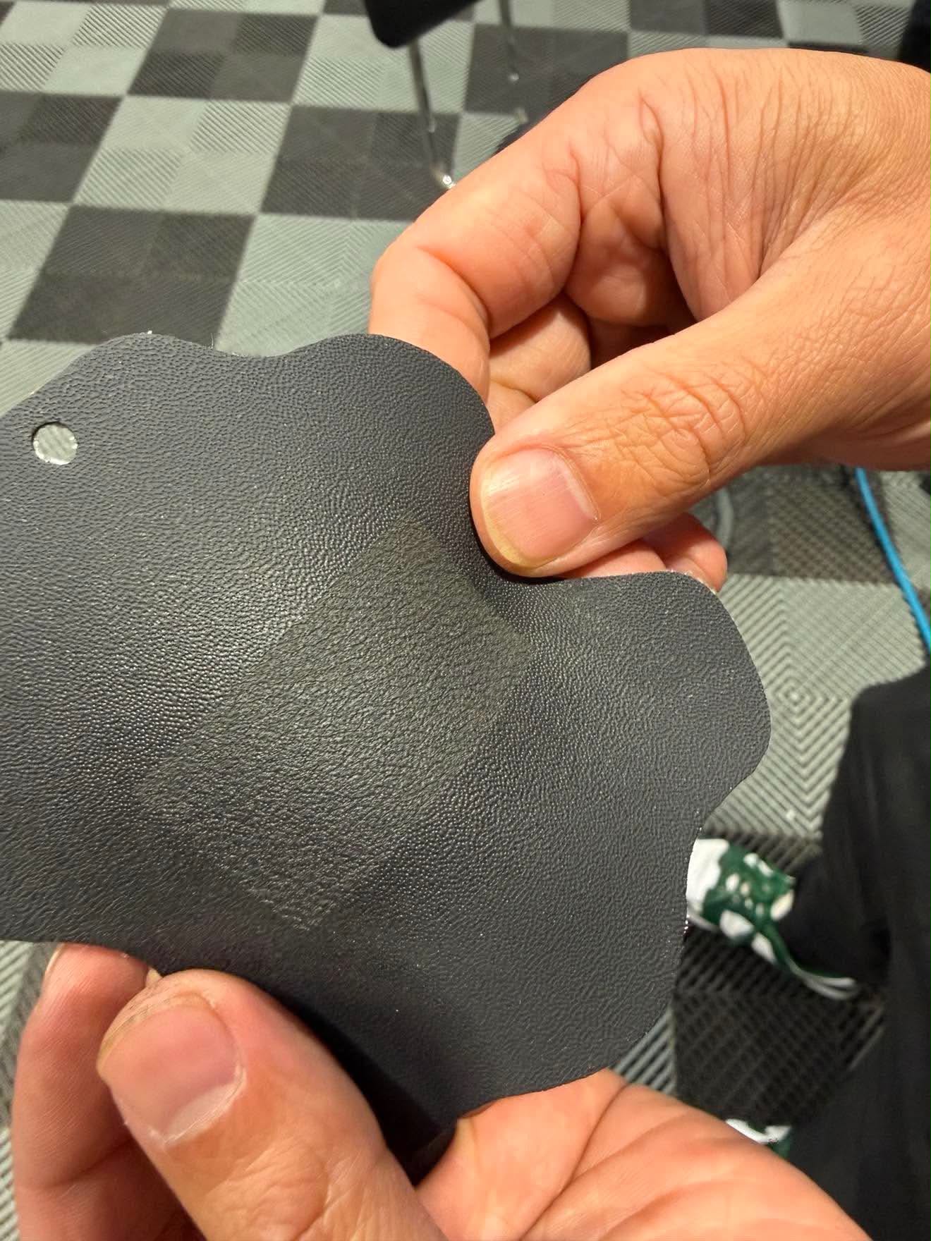 Before and after on one piece of black plastic: the lower area is smooth with no grain, the upper area has been laser regrained with a fine factory style texture
